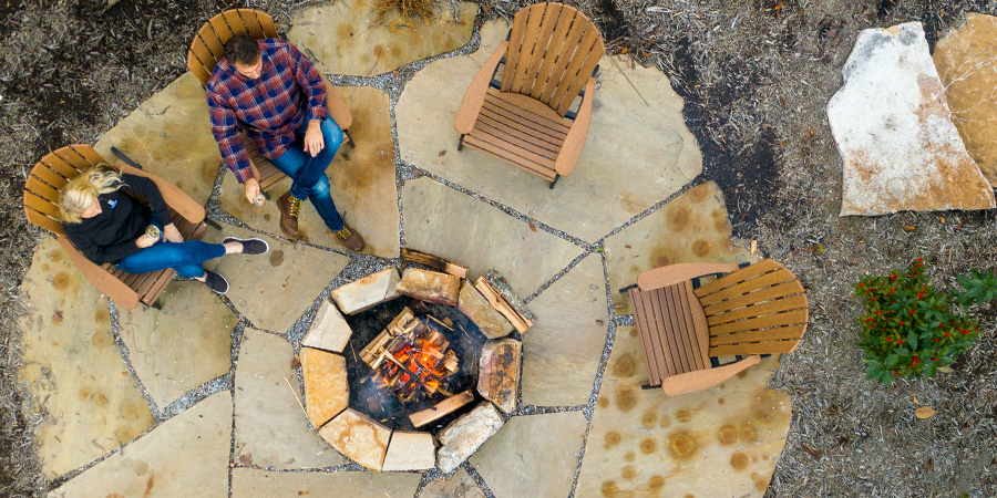 A firepit from above. A man and a woman are relaxing beside the fire.
