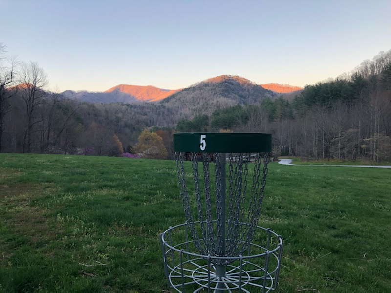 A disc golf basket with a view of the mountains.